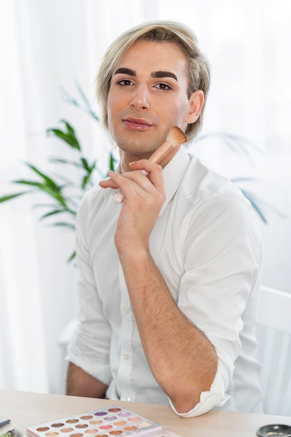 Look de maquillaje masculino sosteniendo un cepillo