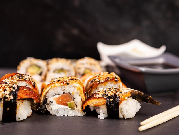Lote mezcla variedad de rollos de sushi sobre fondo de piedra negra en foto de estudio