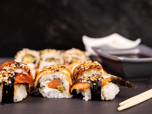 Lote mezcla variedad de rollos de sushi sobre fondo de piedra negra en foto de estudio