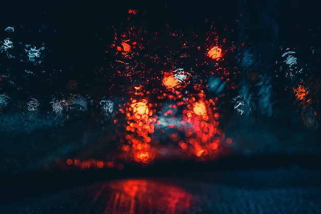 Luces borrosas del automóvil mojado desde el interior de un automóvil