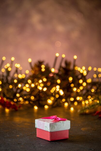 Luces festivas de textura navideña con cajita de regalo en el fondo oscuro aislado