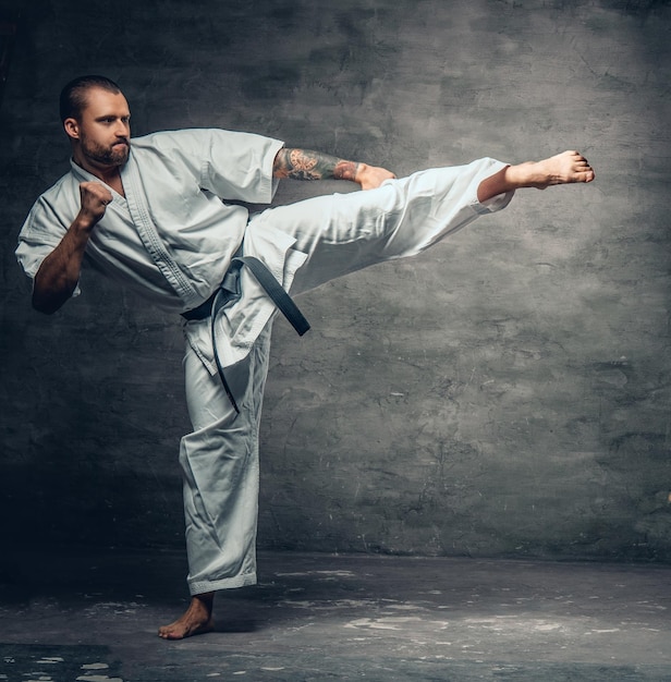 Luchador de karate barbudo vestido con un kimono blanco en acción.
