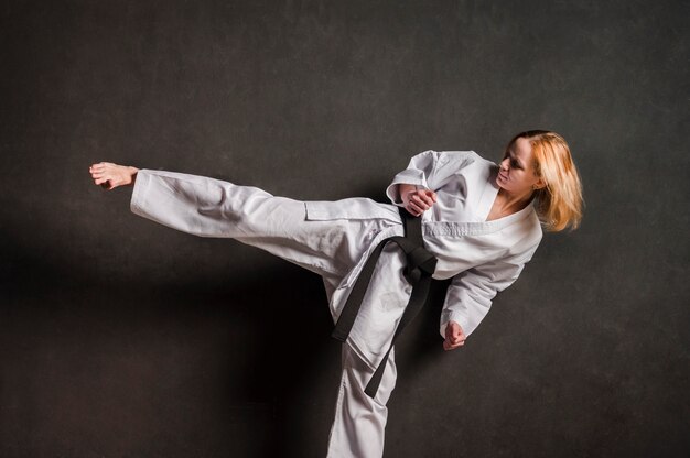 Luchador de karate femenino pateando vista frontal