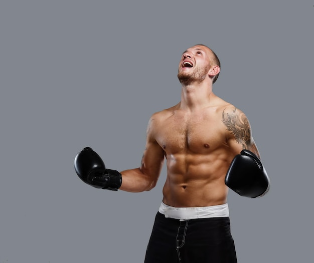 Luchador tatuado agresivo aislado en un fondo gris.