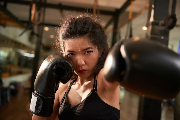 Luchadora haciendo un gesto de golpe hacia la cámara con sus guantes de boxeo