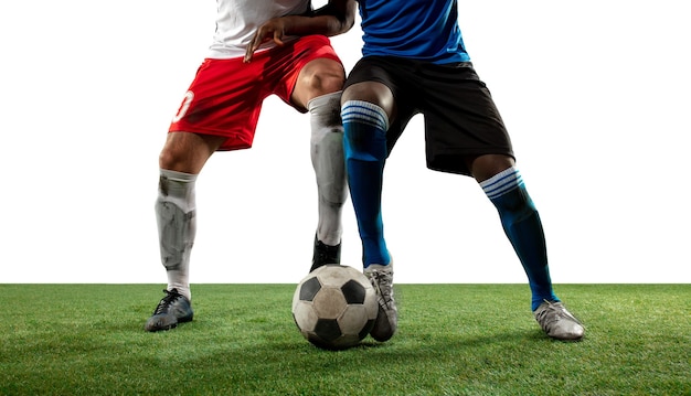 Luchando. Cerrar las piernas del fútbol profesional, jugadores de fútbol que luchan por la pelota en el campo aislado en la pared blanca. Concepto de acción, movimiento, emoción de alta tensión durante el juego. Imagen recortada.