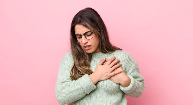 Luciendo triste, herido y con el corazón roto sosteniendo ambas manos cerca del corazón llorando y sintiéndose deprimido