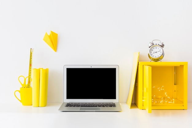 Lugar de trabajo brillante en colores blanco y amarillo con reloj despertador