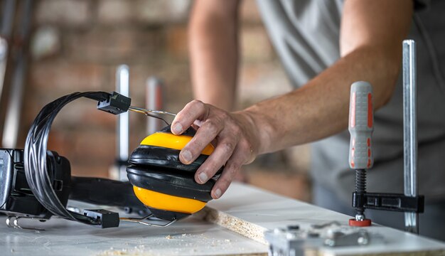 Lugar de trabajo de carpintero profesional con auriculares protectores, protección personal para el trabajo en el taller de producción de carpintería.