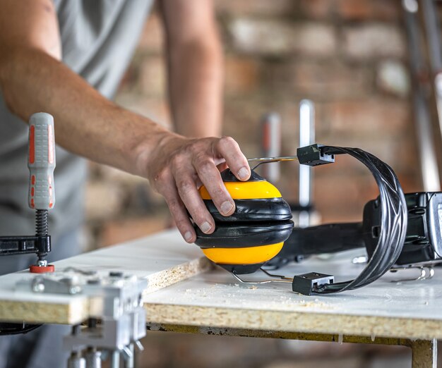 Lugar de trabajo de carpintero profesional con auriculares protectores, protección personal para el trabajo en el taller de producción de carpintería.