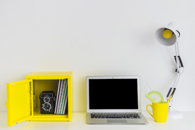Lugar de trabajo elegante blanco en colores blanco y amarillo con ordenador portátil y caja amarilla