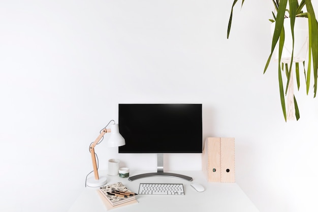 Lugar de trabajo de madera minimalista con monitor en blanco