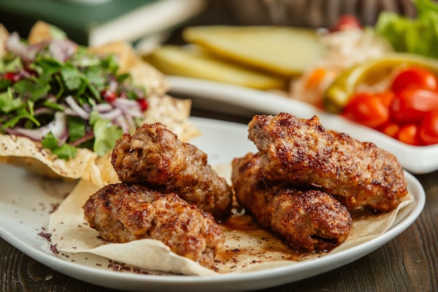 Lula kebab servido con trocitos de cebolla y verduras.