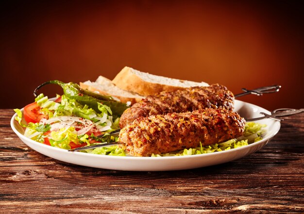 Lule kebab caucásico, barbacoa de carne con ensalada verde y rebanadas de pan,