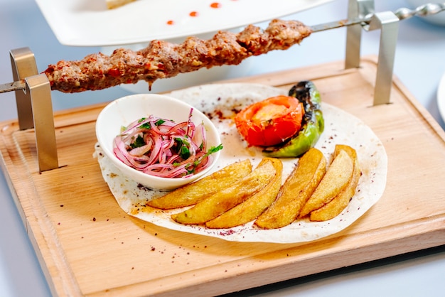 Lule kebab y patata frita con verduras y cebolla.