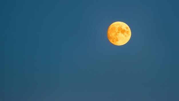 Luna llena amarilla sobre un cielo azul