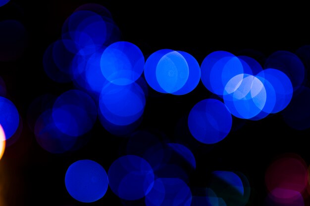 La luz azul circular abstracta borrosa bokeh sobre fondo oscuro