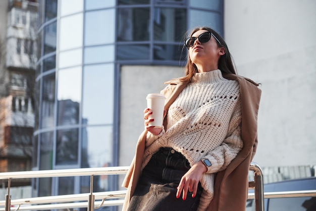 Foto gratuita luz natural. hermosa joven en ropa de abrigo tiene caminar en la ciudad en su tiempo de los fines de semana