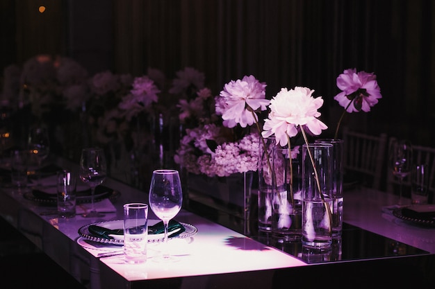 Luz violeta sobre la mesa puesta con flores.