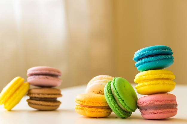 Foto gratuita macarones coloridos apilados en una mesa blanca