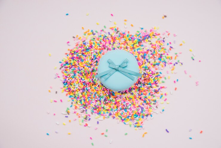 Foto gratuito macarons azules sobre las chispitas coloridas en fondo coloreado