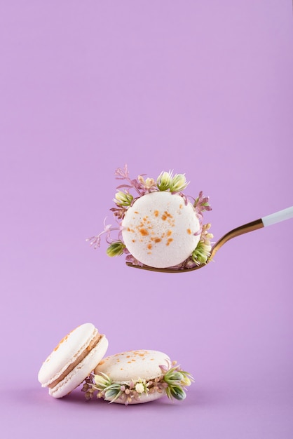 Macarons ecológicos con flores sobre fondo morado