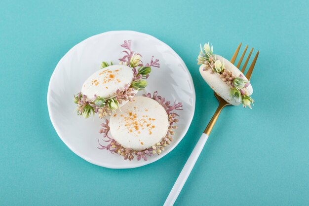 Macarons ecológicos con flores en la vista superior del plato