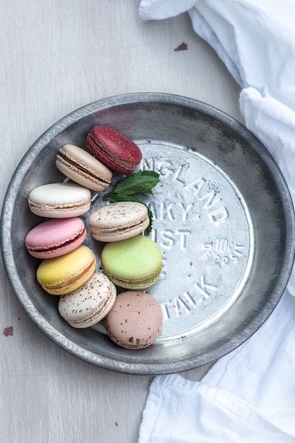 Macarons franceses de diferentes colores servidos en una placa de plata metálica.