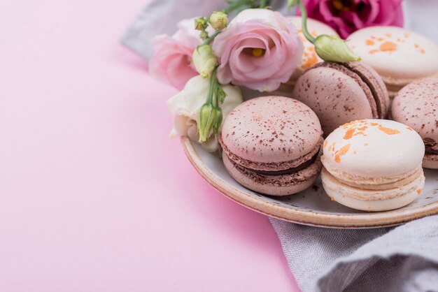 Macarons en plato con rosas y espacio de copia