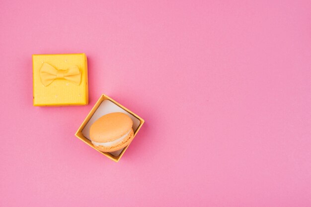 Macarrón naranja en caja de regalo amarilla con espacio de copia