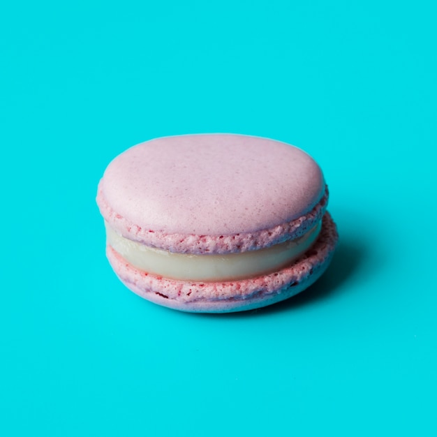 Macarrón rosa con crema sobre fondo azul