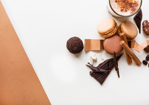 Macarrones; Bola de chocolate y vaso de café con ingredientes sobre fondo blanco