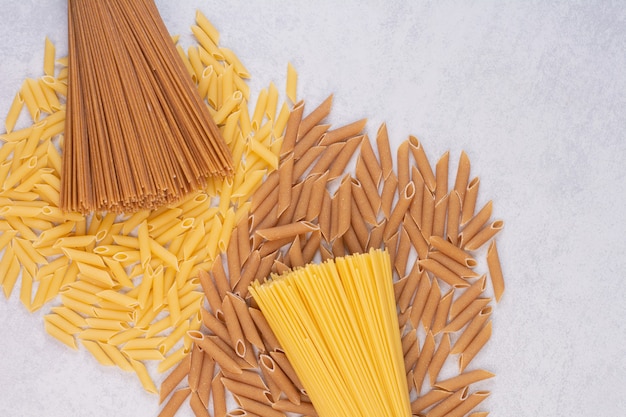 Macarrones sin cocer con pasta cruda fresca sobre superficie blanca