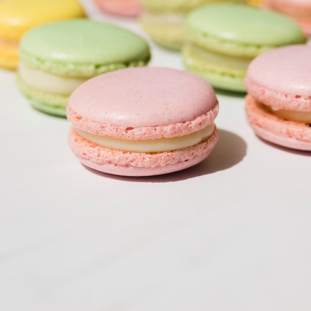 Macarrones de crema batida verde y rosa sobre fondo blanco