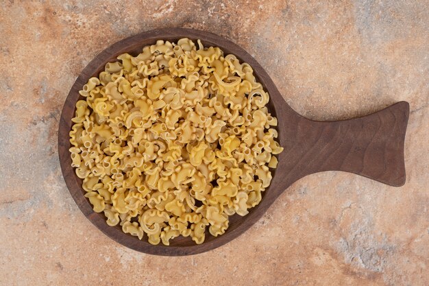 Macarrones crudos frescos sobre tabla de madera sobre fondo de mármol