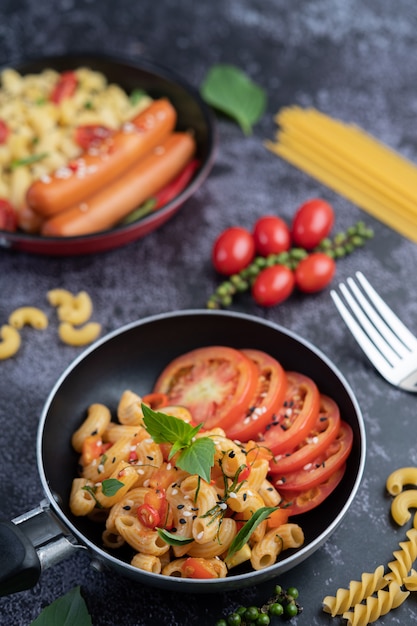 Macarrones fritos y salchichas en una sartén.