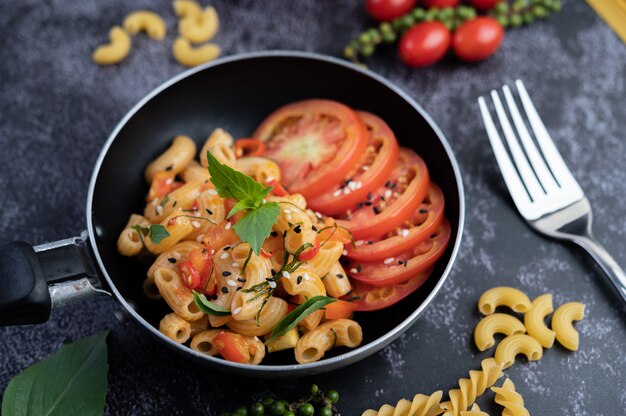 Macarrones fritos y salchichas en una sartén.