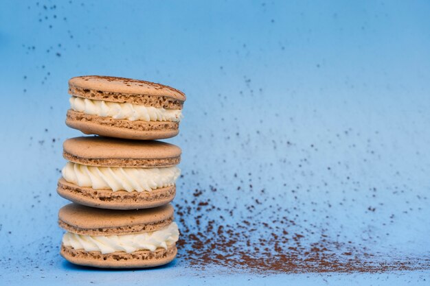 Macarrones marrones con crema batida sobre fondo azul