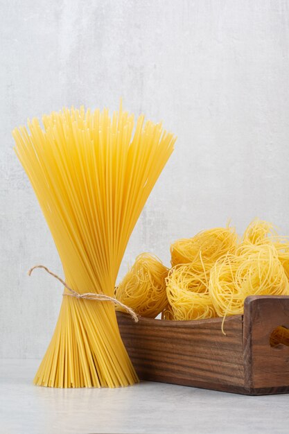 Macarrones y pastas crudos frescos sin cocinar en cesta de madera.