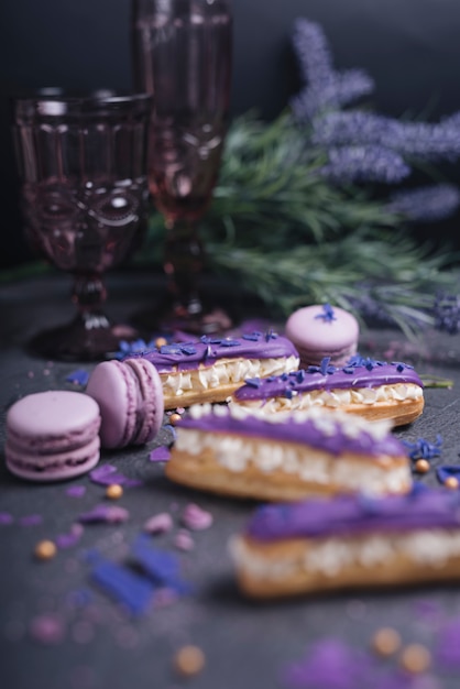 Macarrones púrpuras que caen del vidrio decorativo en fondo texturizado oscuro