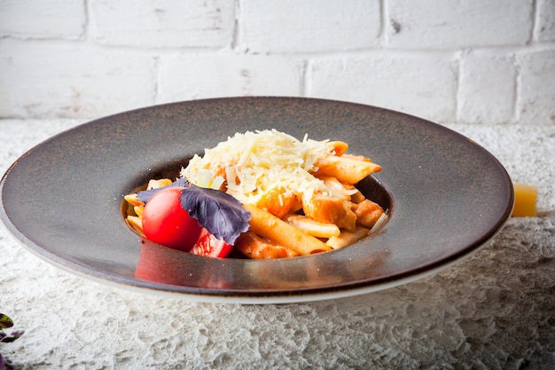 macarrones con queso y tomate y albahaca morada en plato redondo