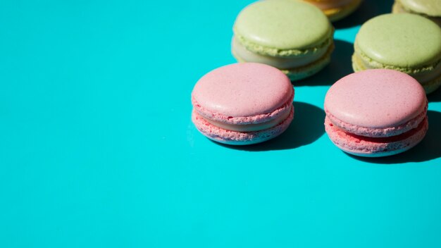 Macarrones rosados y verdes sobre fondo turquesa