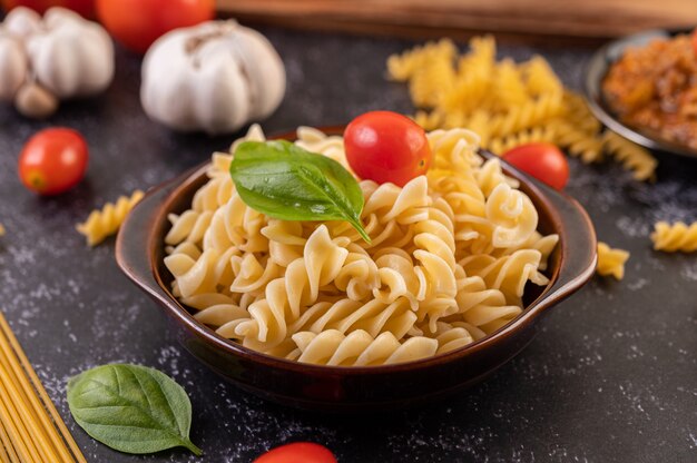 Macarrones salteados con tomate y albahaca en una placa gris.