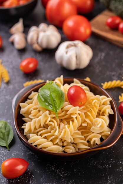 Macarrones salteados con tomate y albahaca en una placa gris.