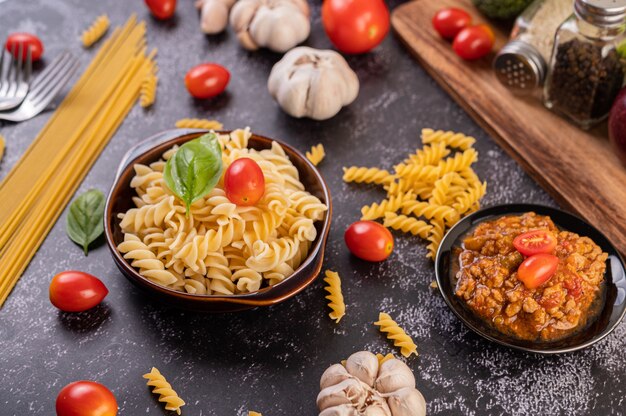 Macarrones salteados con tomate y albahaca en una placa gris.