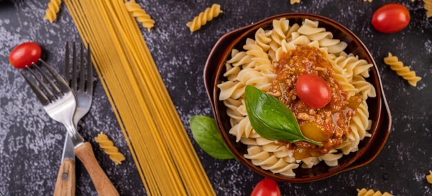 Macarrones salteados con tomate y albahaca en una placa gris.