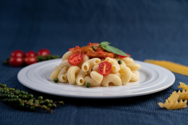 Macarrones salteados con tomate, chile, pimiento y albahaca en un plato blanco.