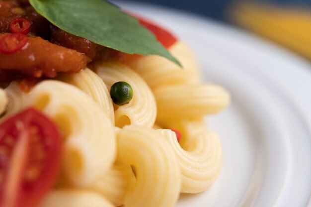 Macarrones salteados con tomate, chile, pimiento y albahaca en un plato blanco.