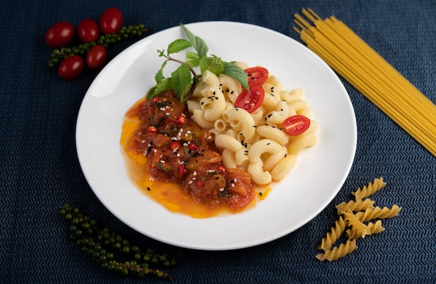 Foto gratuita macarrones salteados con tomate, chile, pimiento y albahaca en un plato blanco.