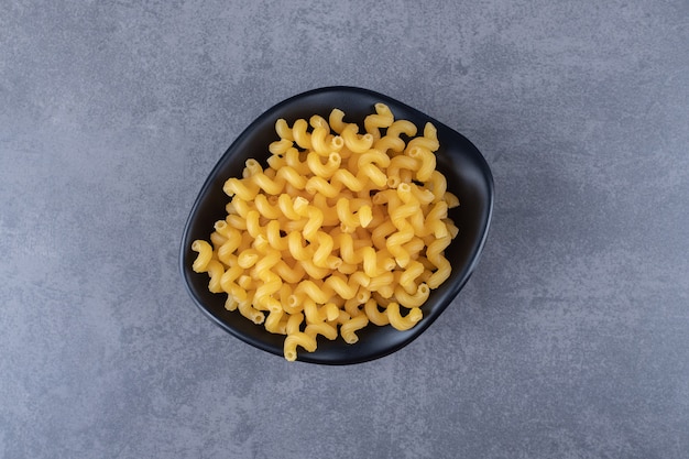 Macarrones secos crudos en un tazón negro.